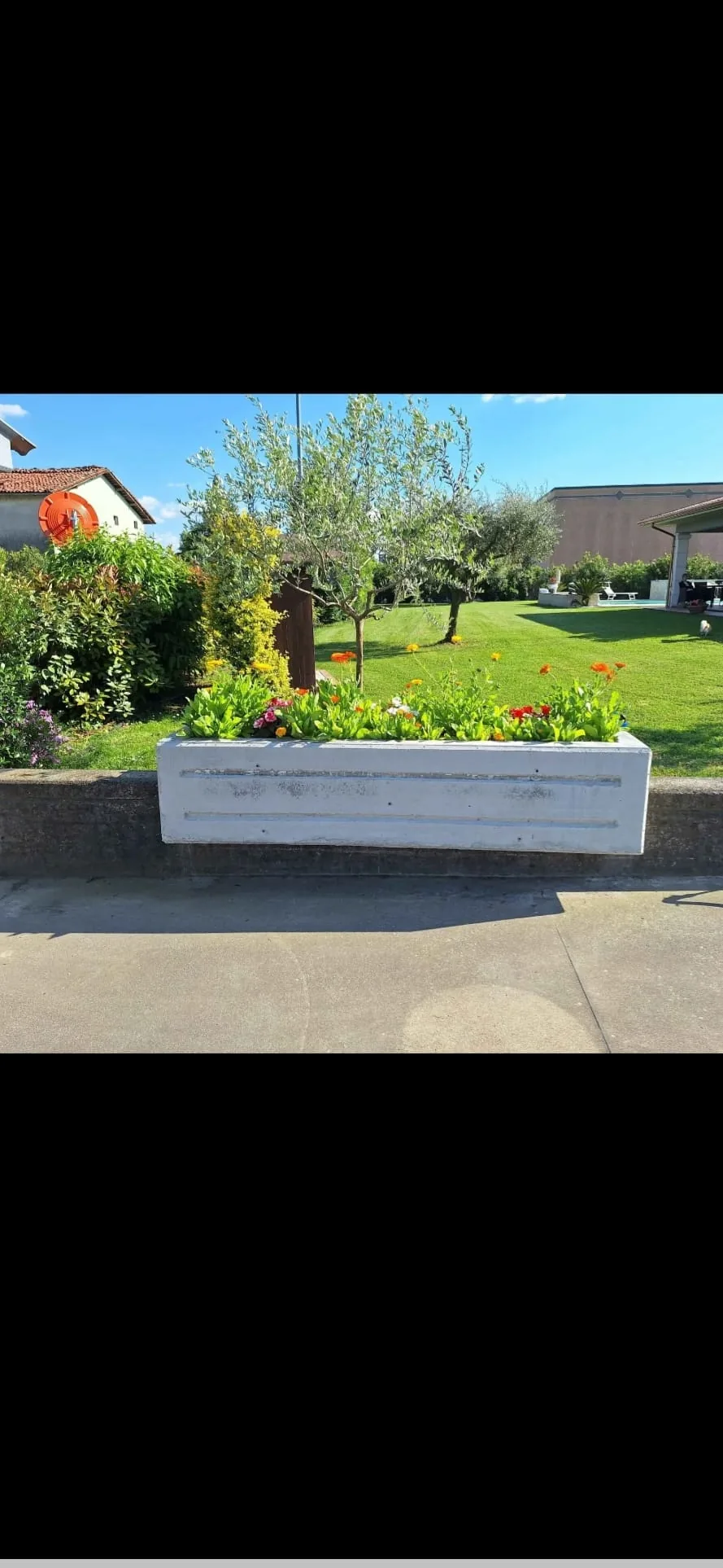 Fioriera installata davanti a un giardino di villa privata con composizione floreale e ulivo